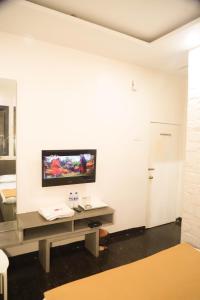 a living room with a tv on a white wall at Hotel Maharaja in Thane
