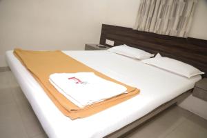 a bed with a brown and white blanket on it at Hotel Maharaja in Thane