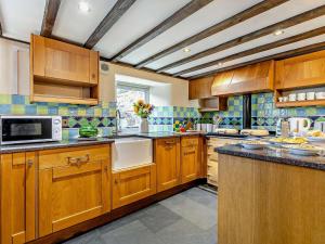 a kitchen with wooden cabinets and a microwave at 2 Bed in Launceston oc-92551 in Saint Giles on the Heath +18 photos