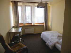 a bedroom with a bed and a desk and a window at Hotel Sowa in Częstochowa