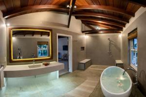 a bathroom with a tub and a sink and a mirror at Cinnamon Room Four-Poster Bed, Freestanding Bath, Walk-In Shower & Infinity Pool in Cap Malheureux +41 photos