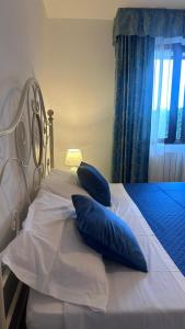 a white bed with blue pillows on it at Stella Marina in Olbia