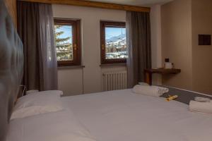 a bedroom with a large white bed with two pillows at Hotel Gran Roc in Sestriere