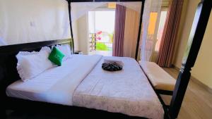 a bedroom with a large bed with white sheets and green pillows at Amara Kivu Resort in Île Bugarura
