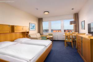 a hotel room with a bed and a table and chairs at IFA Yachthafen Fehmarn in Fehmarn