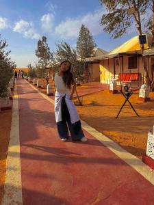 a woman standing on the side of a road at Camel Trekking Camp & Activities in Merzouga
