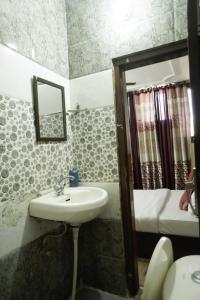 a bathroom with a sink and a mirror and a bed at Hotel Majestica 22 in Chandīgarh
