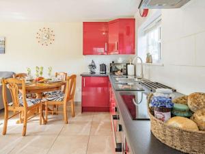 a kitchen with red cabinets and a dining table at 2 Bed in Bude oc-86920 in Kilkhampton