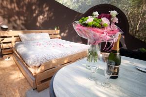 a table with a bottle of champagne and a vase of flowers at La sphère de Raphaël in Saint-Hubert
