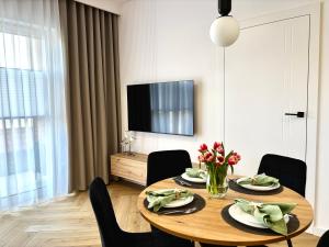 a dining room with a table with chairs and a television at Apartament Kaszubska Bryza III - HEL in Hel