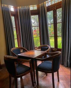 a wooden table and chairs in a room with windows at Malwatte Bungalows in Hali Ela