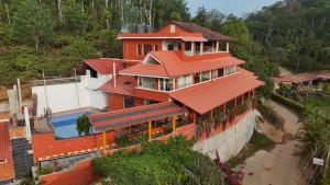 a house with a red roof and a pool at Deva Maani Coorg Nature View in Madikeri