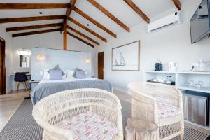 a bedroom with a bed and two wicker chairs at Elephant Hide of Knysna Guest Lodge in Knysna