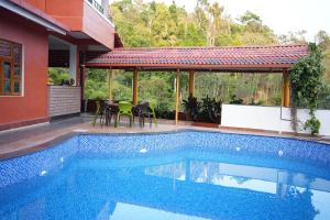 a swimming pool with tables and chairs next to a house at Deva Maani Coorg Nature View in Madikeri