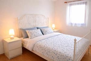 a bedroom with a white bed with blue pillows at Apartmani Ribarica**** in Karlobag