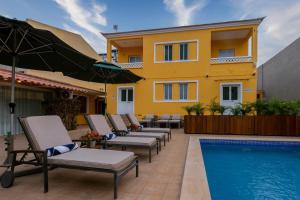 a patio with chairs and a pool and a building at Kululwa House in Luanda