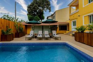 a swimming pool in front of a house with chairs and umbrellas at Kululwa House in Luanda