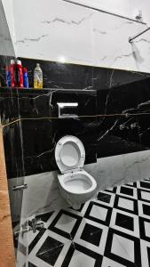 a black and white bathroom with a toilet in a room at Adiyogi Guest House in Ujjain +2 photos