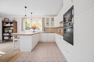 a kitchen with white cabinets and a tile floor at Summer Dream in De Haan +18 photos