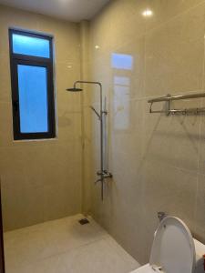 a bathroom with a shower with a toilet and a window at Carol Dalat in Khu Chi Lăng