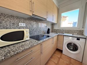 a kitchen with a microwave and a washing machine at Agi Josep Sabater in Roses