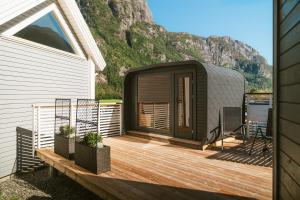 a tiny house with a deck next to a mountain at Frafjord Apartments Frøya in Dirdal