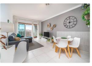 a living room with a table and chairs and a clock at Sunny apartamento in Portimão