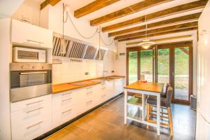 a kitchen with white cabinets and a wooden table at Espectacular casa rural en el corazón del Baztán in Ziga