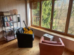 a living room with two chairs and a television and a guitar at Servus Almtal in Scharnstein