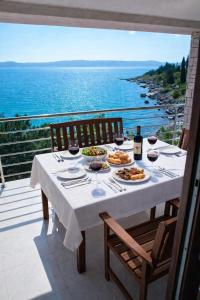 a table with food and wine on a balcony with the ocean at Apartmani Ribarica**** in Karlobag