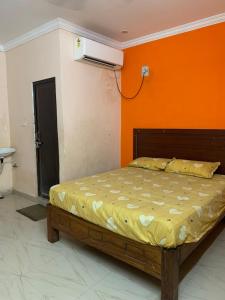a bed in a room with an orange wall at Amaravathi Convention & Function hall in Penuganchiprolu