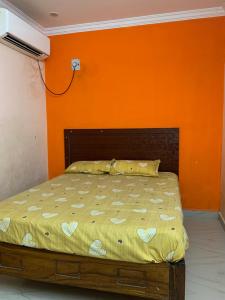 a bed in a room with an orange wall at Amaravathi Convention & Function hall in Penuganchiprolu