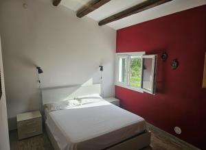 a bedroom with a white bed and a red wall at Podere Al Covo - House, Garden & Vineyard - Alghero in Alghero