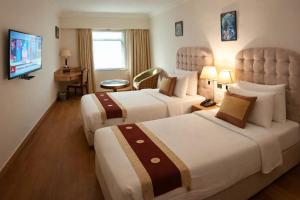 a hotel room with two beds and a television at Hotel Saj Luciya in Trivandrum