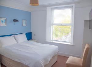 a bedroom with a white bed and a window at The Tremont in Penzance