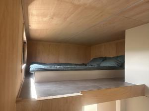 a bed in a small room with a wooden ceiling at Tiny House du Gad Bourgeois in Chièvres