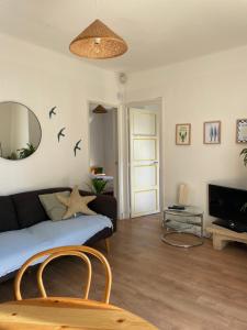 a living room with a couch and a tv at La petite maison près de la mer, avec jardin , parking et clim in La Ciotat