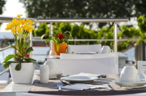 a table with plates and a vase with yellow flowers on it at RK Beach Hotel in Kamari