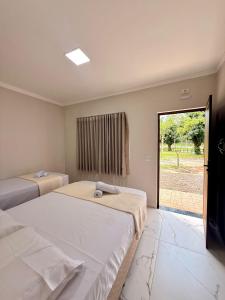 a bedroom with two beds and a sliding glass door at Hotel e Pousada Martini in Sorriso