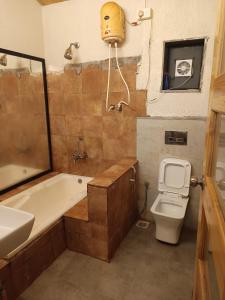 a bathroom with a tub and a toilet and a sink at Harmal's Residency in Arambol
