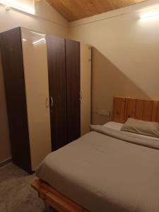 a small bedroom with a bed and a cabinet at Harmal's Residency in Arambol
