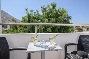 a table with two glasses and a book on a balcony at RK Beach Hotel in Kamari