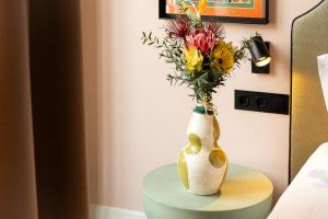 a vase with flowers in it sitting on a table at The Mila Porto in Porto