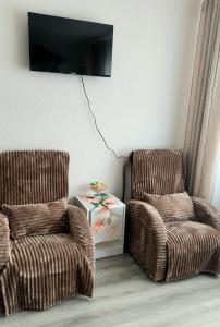 two chairs in a living room with a tv on the wall at Ciemos pie Ingas Sedā in Seda