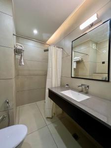 a bathroom with a sink and a mirror and a toilet at Hotel Mango Groves in Kotdwāra