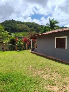 a house with a grass yard next to a building at Chalé Triunfo in Pacoti