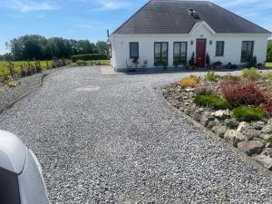 a gravel driveway in front of a white house at Shanboley Cottage in Ballinasloe