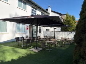 a patio with tables and chairs under an umbrella at Hotel Bremer Kreuz in Achim