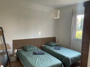 a room with two beds and a window at La petite maison près de la mer, avec jardin , parking et clim in La Ciotat
