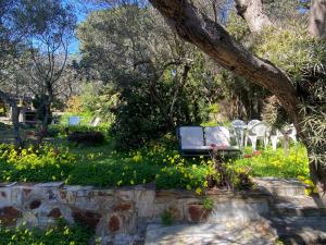 a park with a bench and chairs and flowers at La Caseta de Cadaqués in Cadaqués